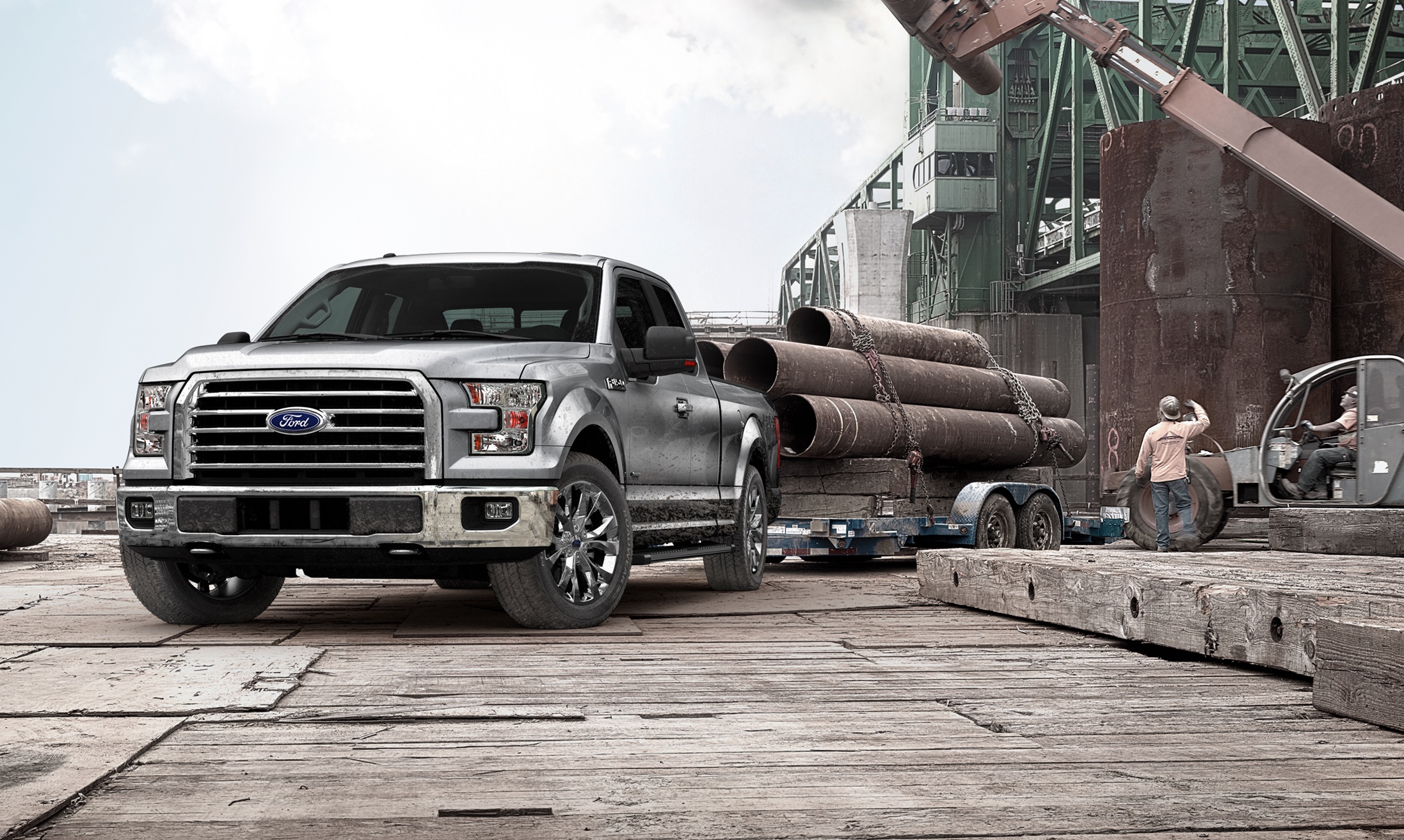 Silver Ford F-150 hauling industrial pipe at a working waterfront